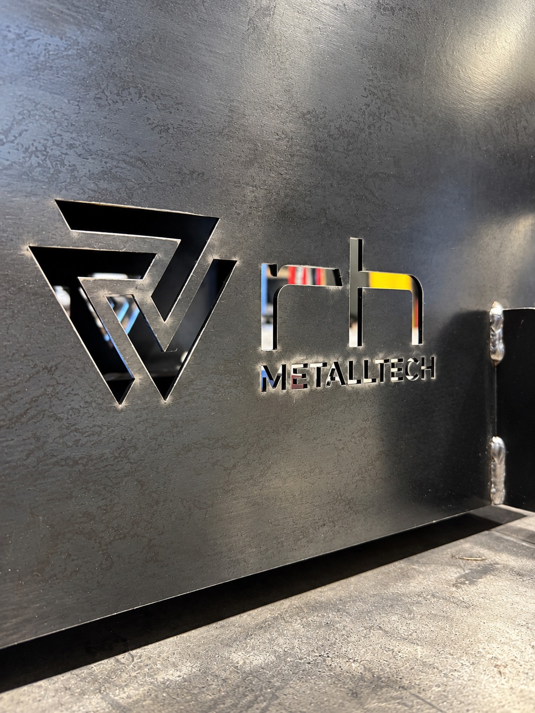 RH Metalltech Logo als ausgeschnittenes Metallelement an einer Werkstattwand